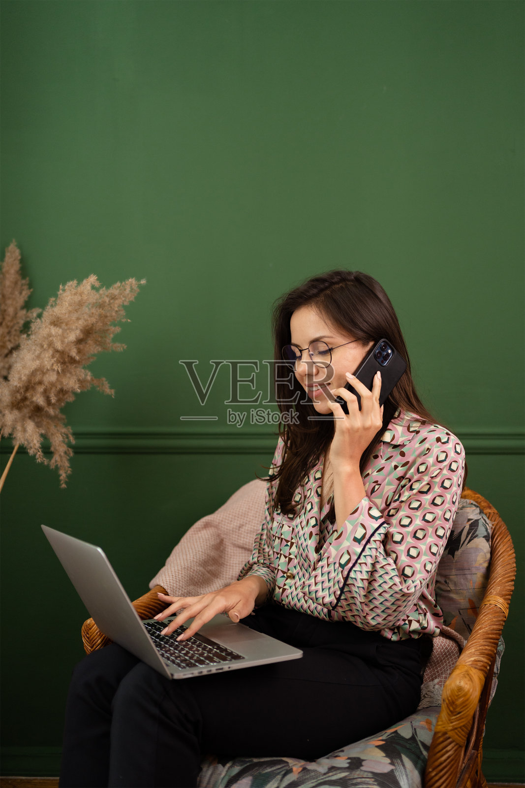 愉快的年轻美丽的女人在电话和使用笔记本电脑照片摄影图片