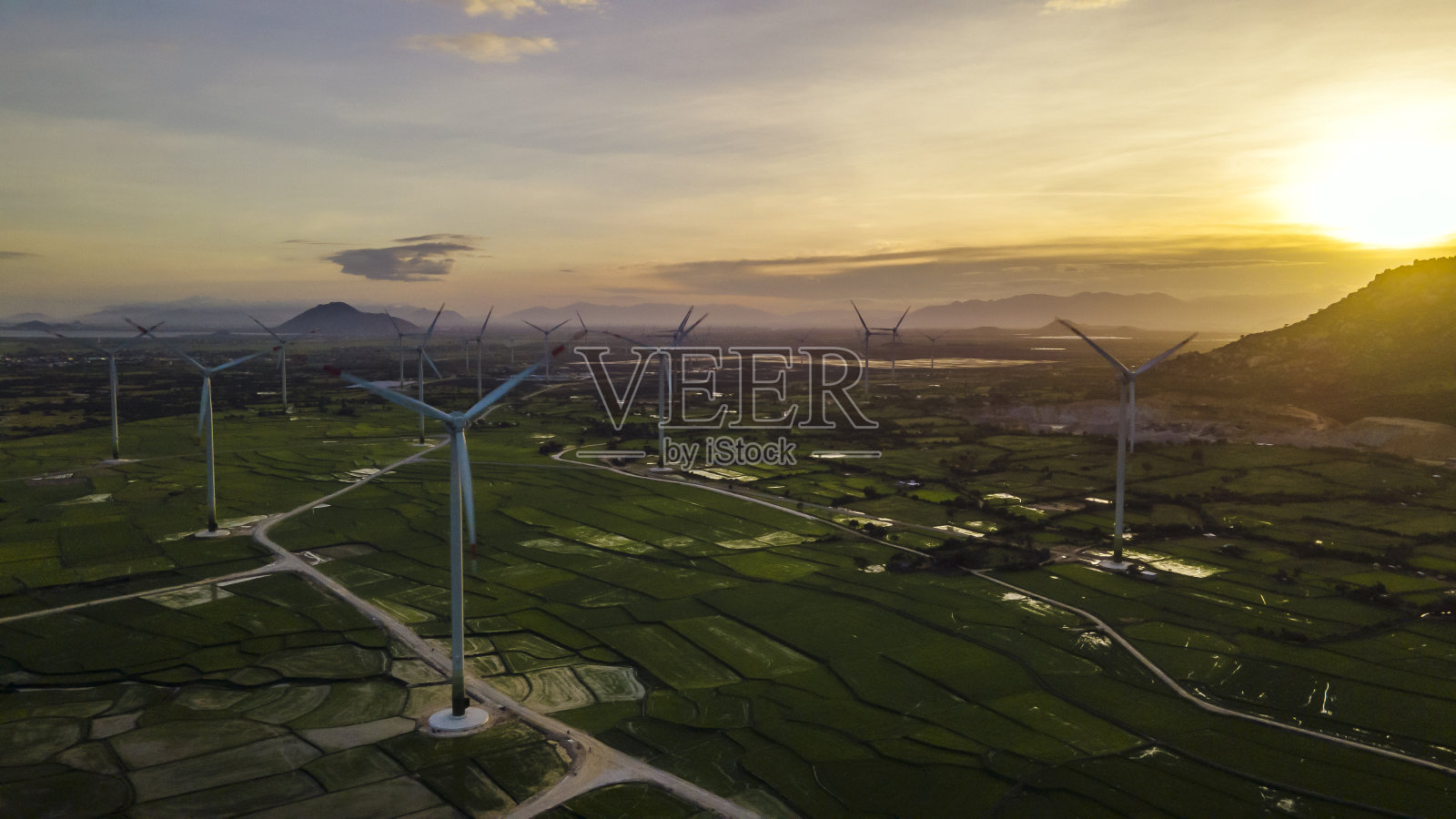 无人机拍摄的风力涡轮机塔农场,在蓝天下的一大片绿色稻田里,落日余照,发电可再生风能,支持可持续发展,防止环境污染照片摄影图片