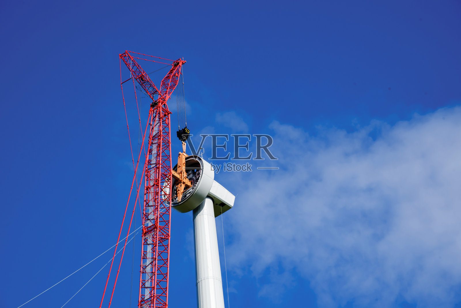 在美丽的蓝天下,一只红色的大鹤正在建造风力涡轮机塔照片摄影图片