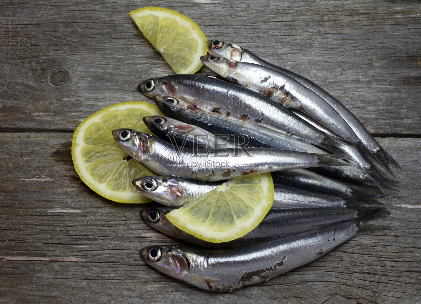 新鲜的沙丁鱼凤尾鱼从市场上买的新鲜柠檬片在旧的木制背景照片摄影图片