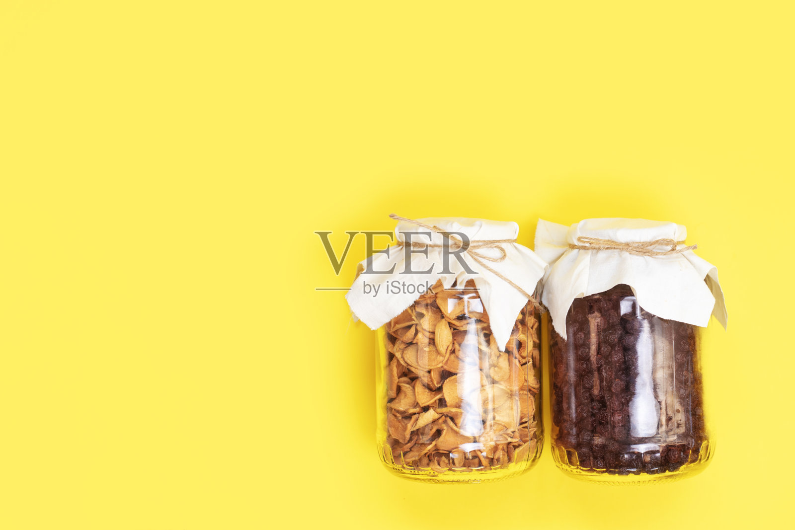 用玻璃罐子装干的有机苹果和樱桃,背景为黄色,有复印空间照片摄影图片