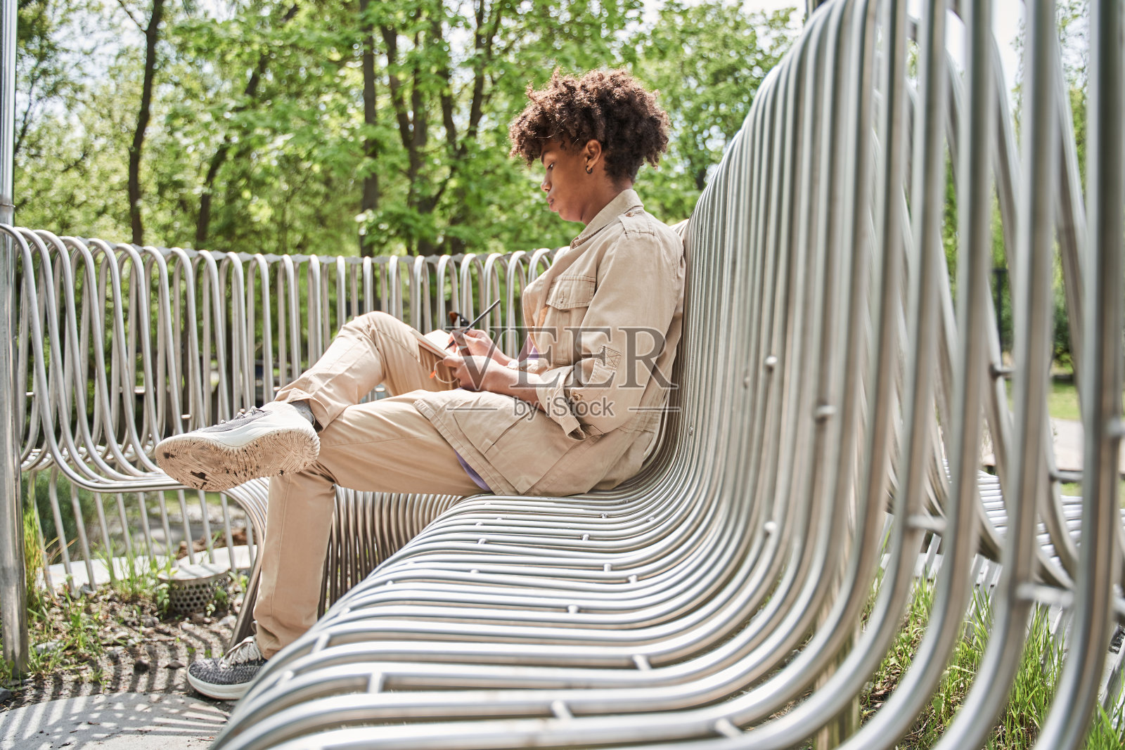 男孩坐在公园的长椅上,在笔记本上写着什么照片摄影图片