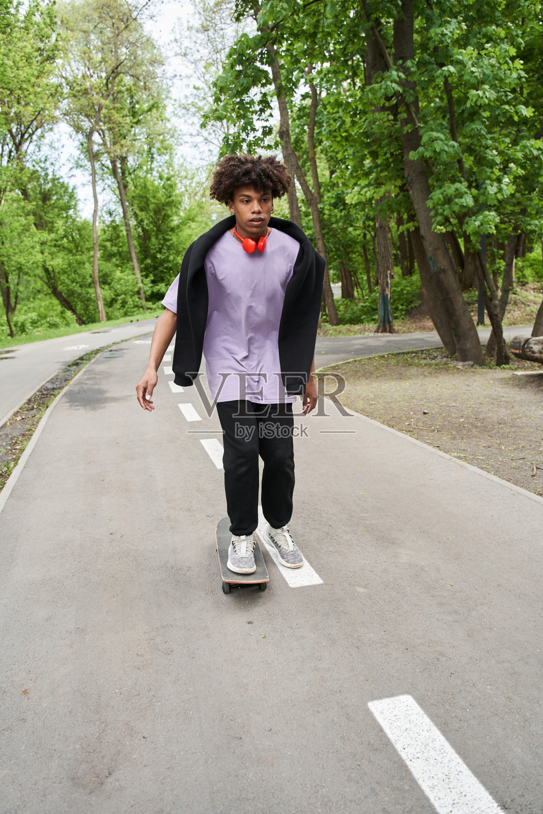 在城市道路上,卷发男子一边练习滑板,一边享受积极的休息照片摄影图片