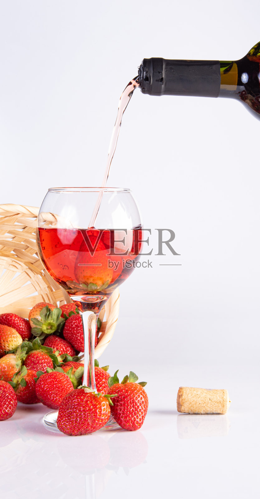 用水晶酒杯盛上玫瑰红葡萄酒,白色表面上点缀着美丽的草莓,选择性的聚焦。照片摄影图片