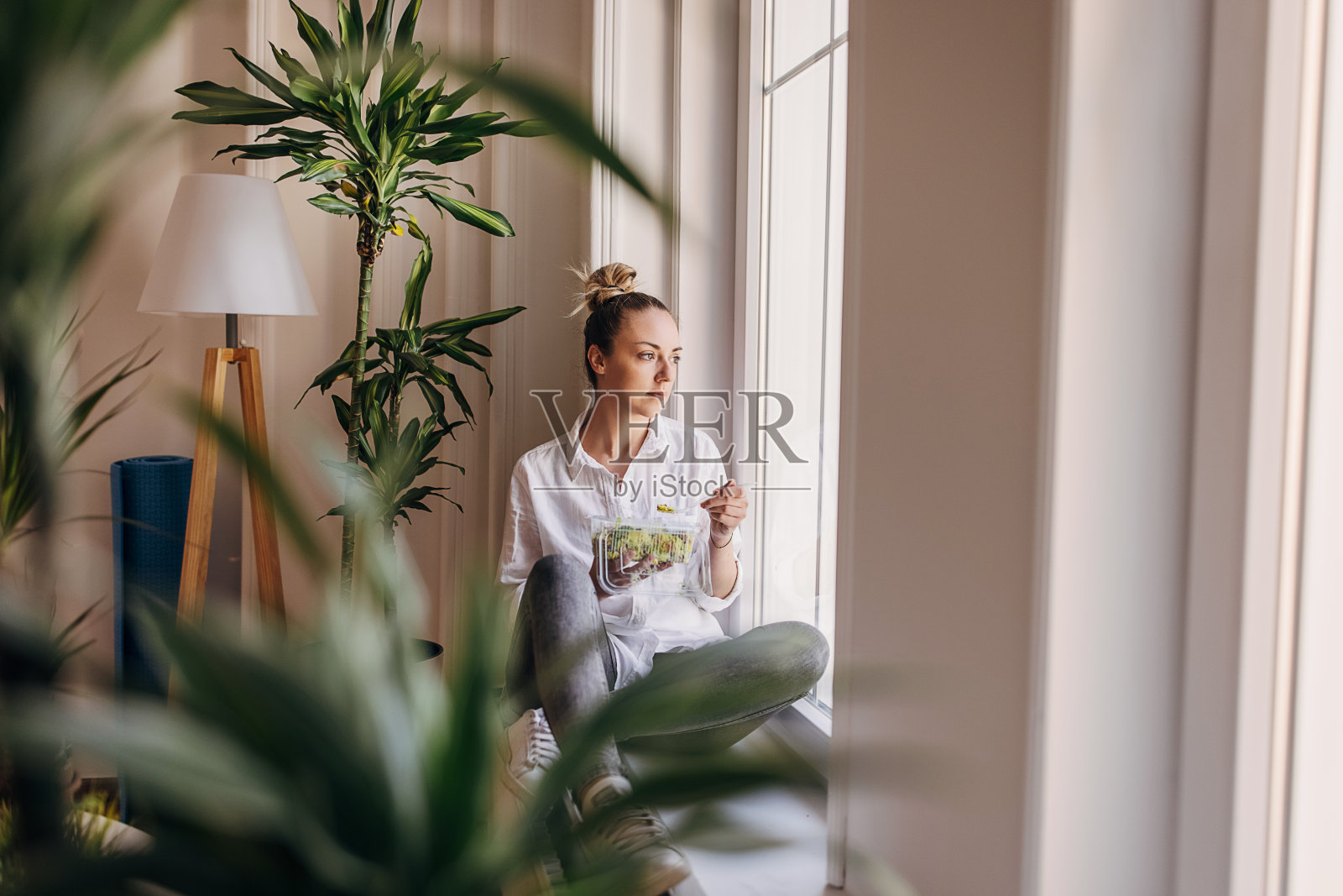 坐在窗边吃新鲜沙拉的女人照片摄影图片