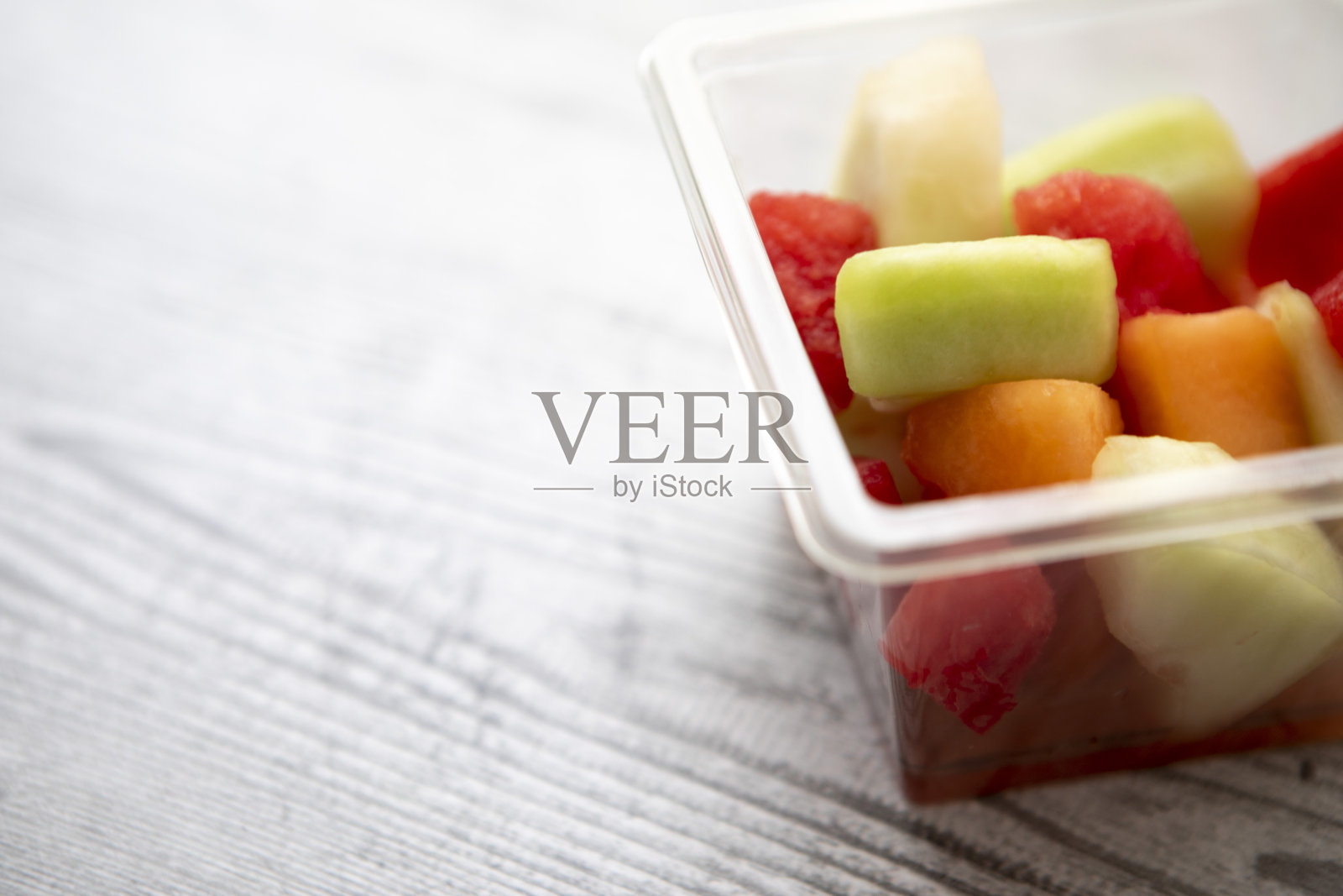 蜜瓜水果沙拉,放在一个方形塑料(聚对苯二甲酸乙酯)桶里,有拷贝空间照片摄影图片