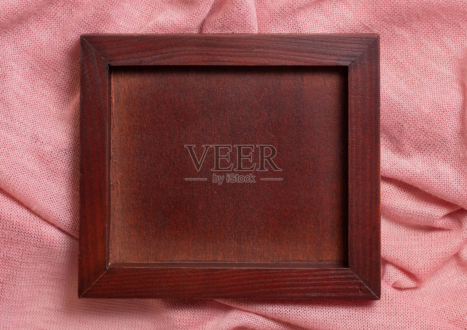 一个木制的空白框架在一个粉红色的织物上从上面看。照片摄影图片
