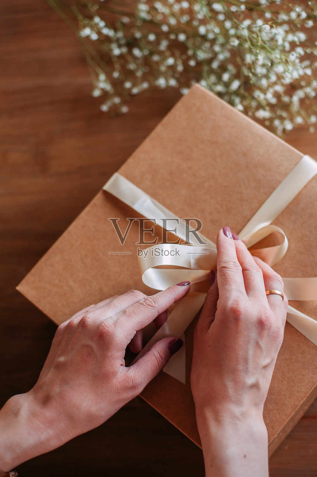 女人的手正在包装或打开礼物。照片摄影图片