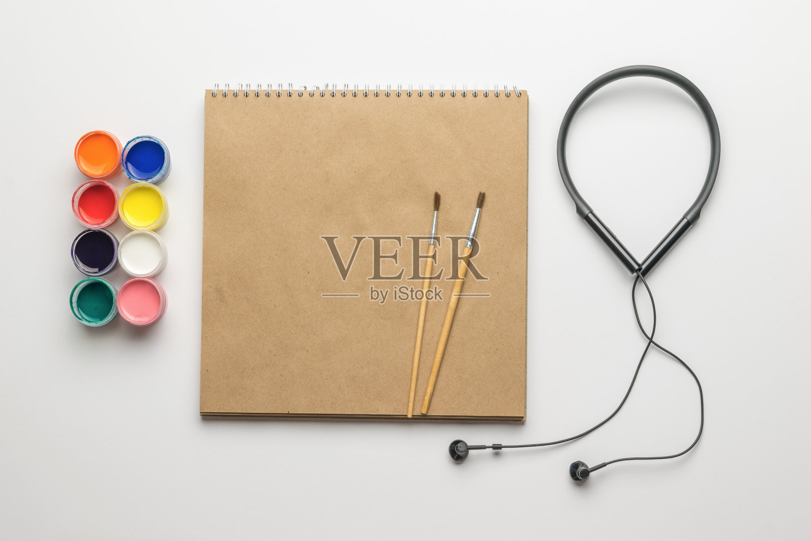 素描本,颜料,耳机和白色背景上的画笔。照片摄影图片