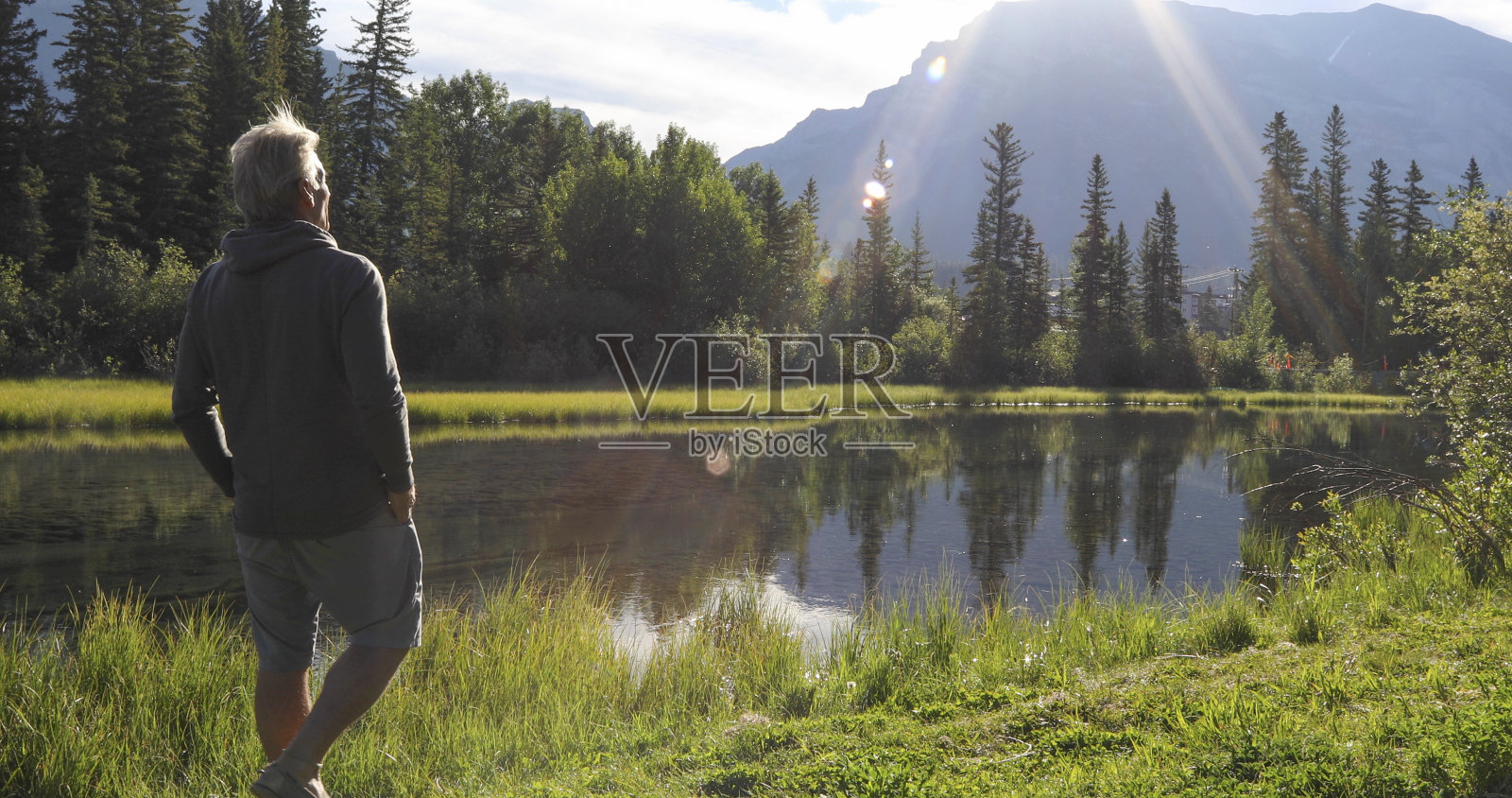 徒步旅行者穿过阳光充足的湖岸附近的沼泽地照片摄影图片