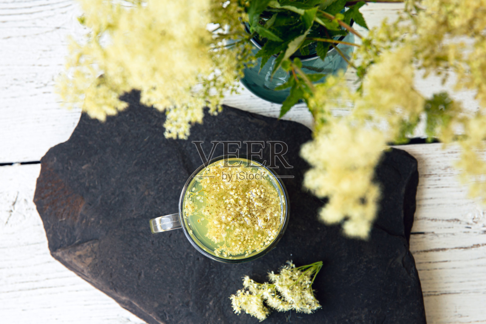 现代以上的观点通过新鲜的绣线菊花,竹莲花在花瓶到同样的植物草本茶在玻璃。照片摄影图片