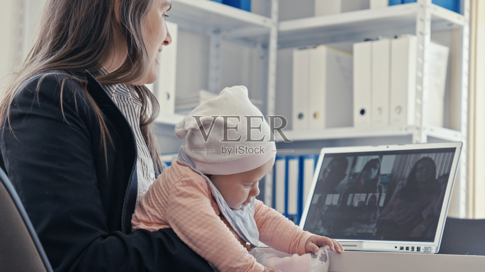 女商人带着孩子在办公室用笔记本电脑召开虚拟会议,新冠肺炎大流行。关闭了。照片摄影图片