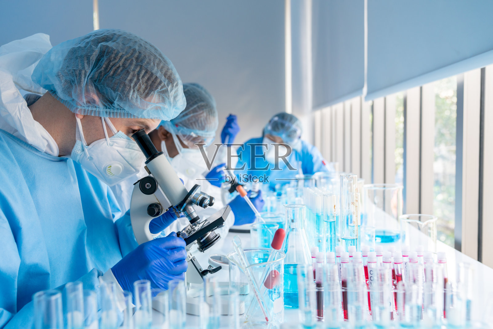 白种科学家在医学实验室使用显微镜研究covid-19病毒疫苗照片摄影图片