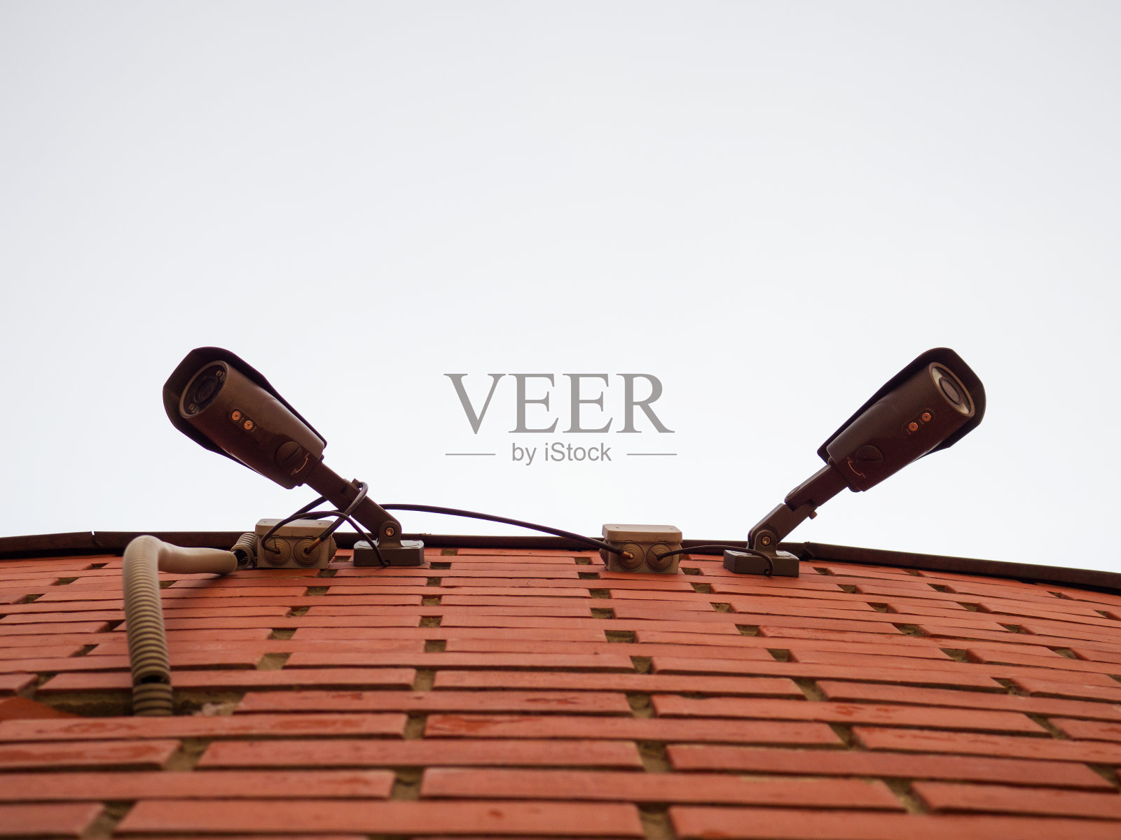 两个摄像头挂在砖墙上。照片摄影图片