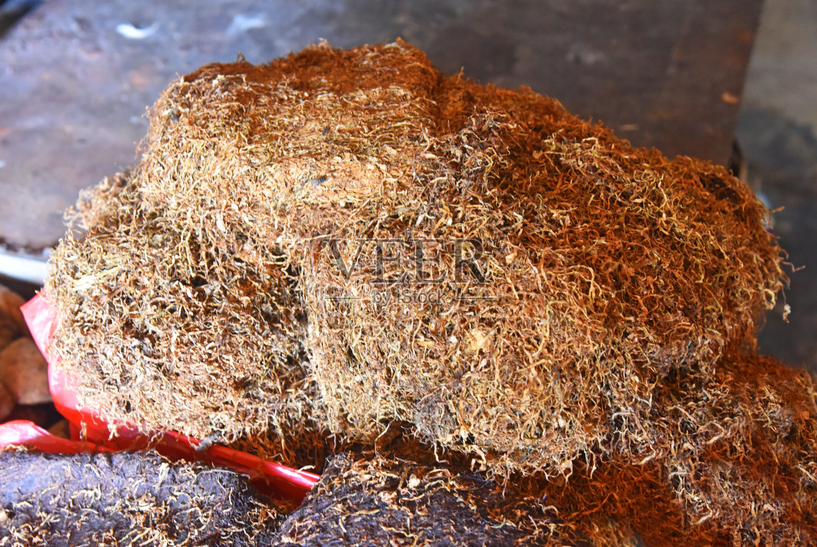 干燥的黑棕色的烟草放置在红色塑料袋在市场上照片摄影图片