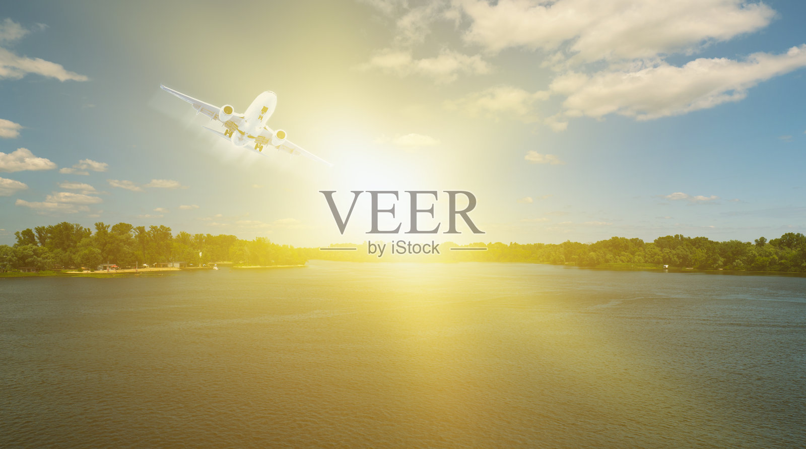 一架客机在一条河和一片森林上空起飞。美丽的天空和云彩。大自然中的日落在水面上。旅行照片摄影图片