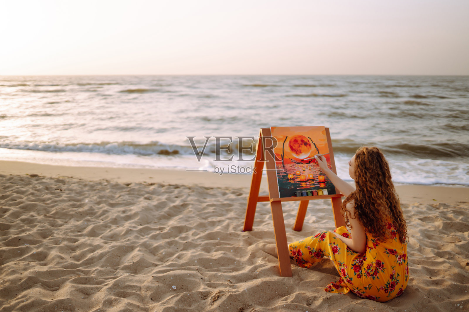 富有创造力的女艺术家在海滩上画画。照片摄影图片