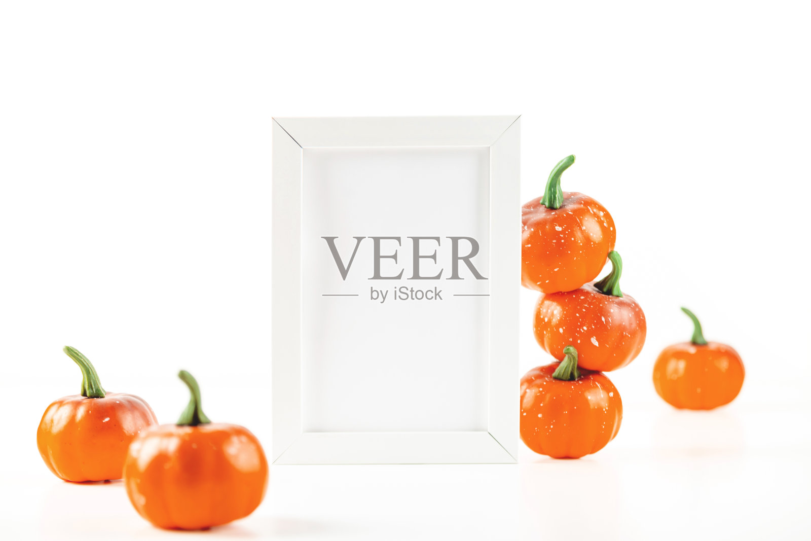 秋季邀请卡的模型或白色框架的设计旁边的橙色小南瓜在白色的背景。照片摄影图片