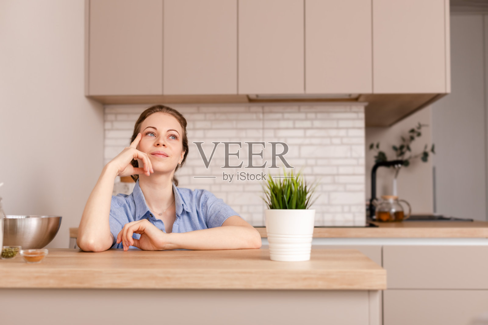 年轻思考女性的肖像厨房室内背景。看一边。照片摄影图片