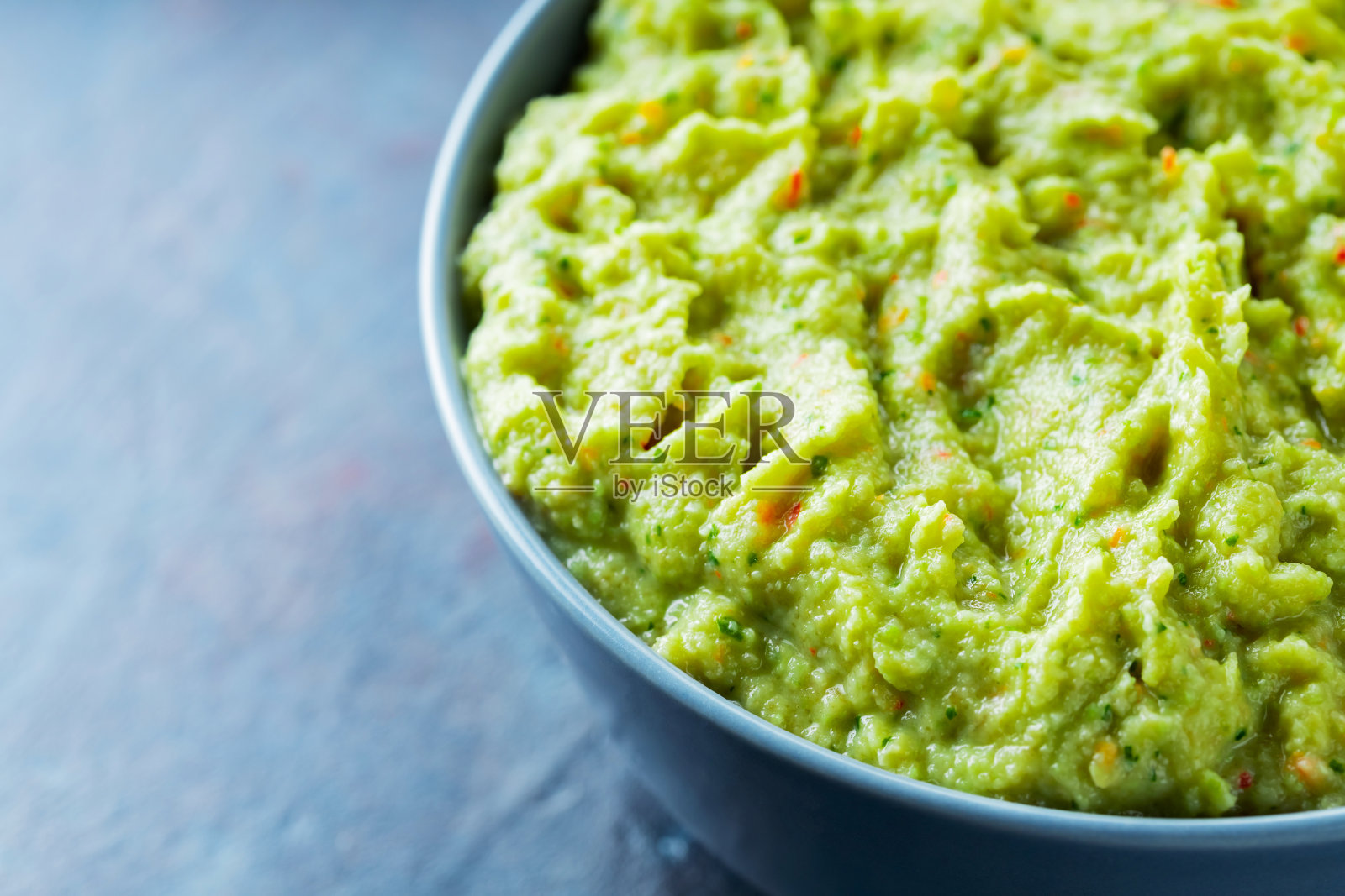 深色背景下灰色碗里的鳄梨酱。一碗新鲜的牛油果鳄梨酱。副本的空间。俯视图照片摄影图片