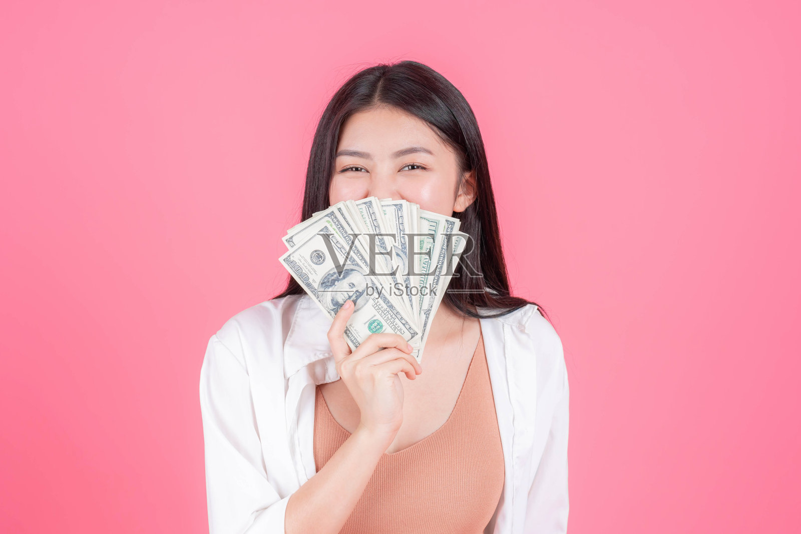 成功美丽的亚洲商业年轻女性手中拿着钞票钞票在粉红色的背景,商业概念照片摄影图片