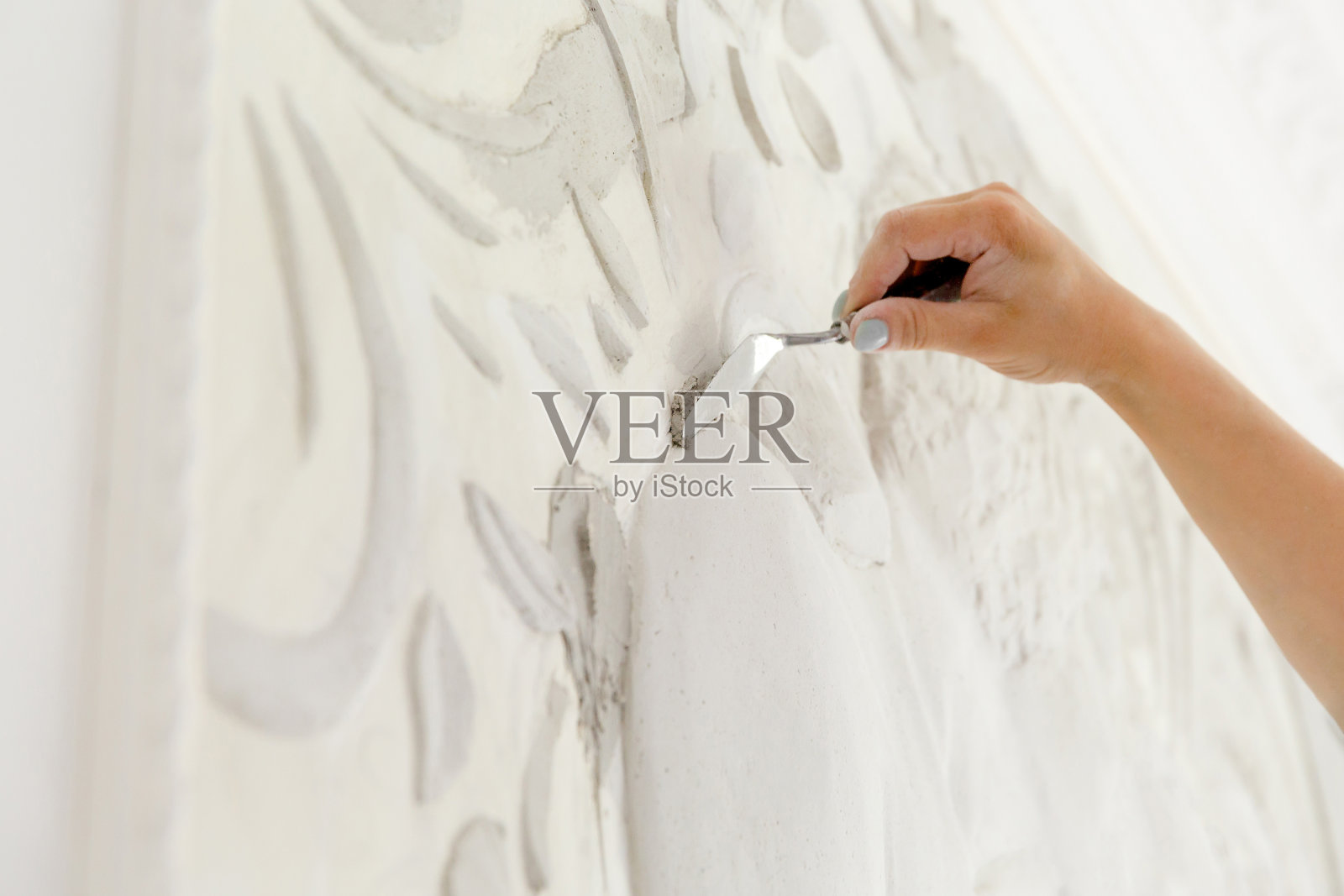 女工人把腻子灰浆放在浅浮雕的墙上照片摄影图片