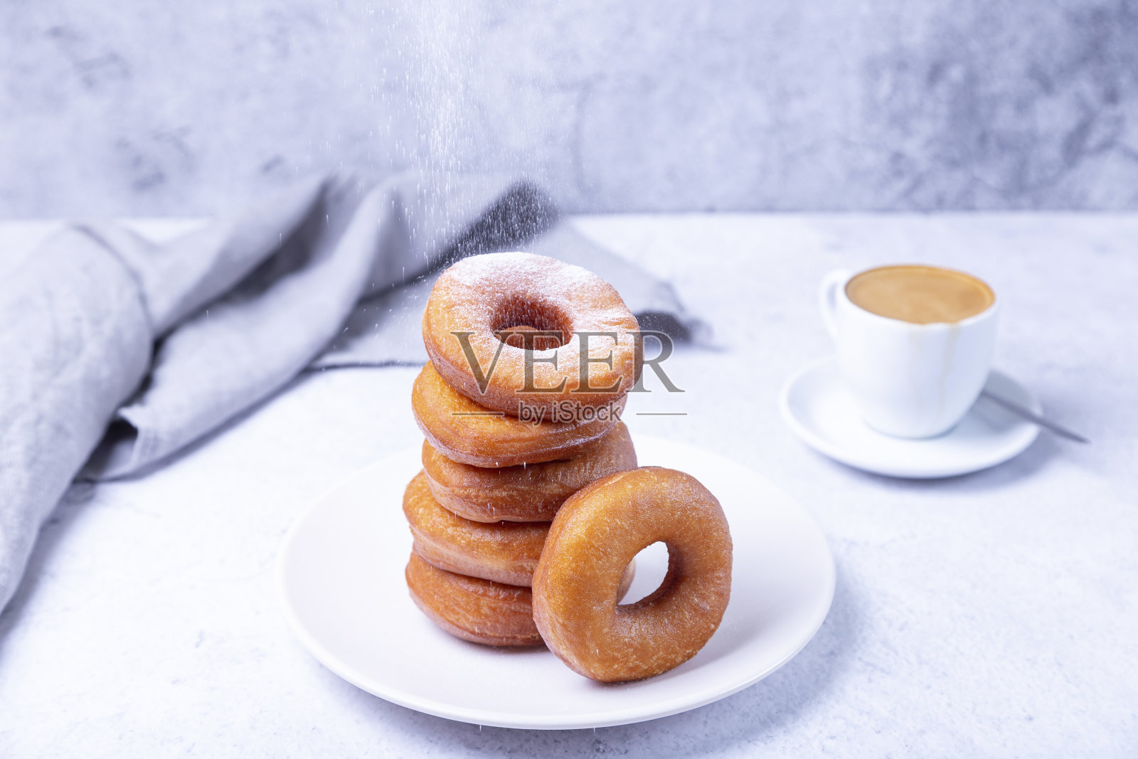 甜甜圈加糖粉和一杯咖啡。传统的环形油炸甜甜圈。有害但美味的食物。照片摄影图片