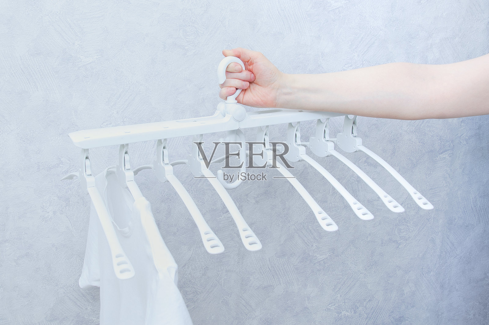 白色塑料衣架,八个衣架在白人妇女的手中。照片摄影图片