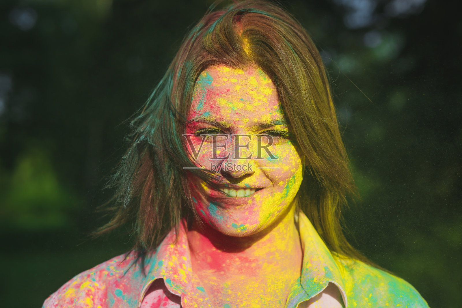 快乐的黑发白人女孩在胡里节玩彩色的干油漆照片摄影图片