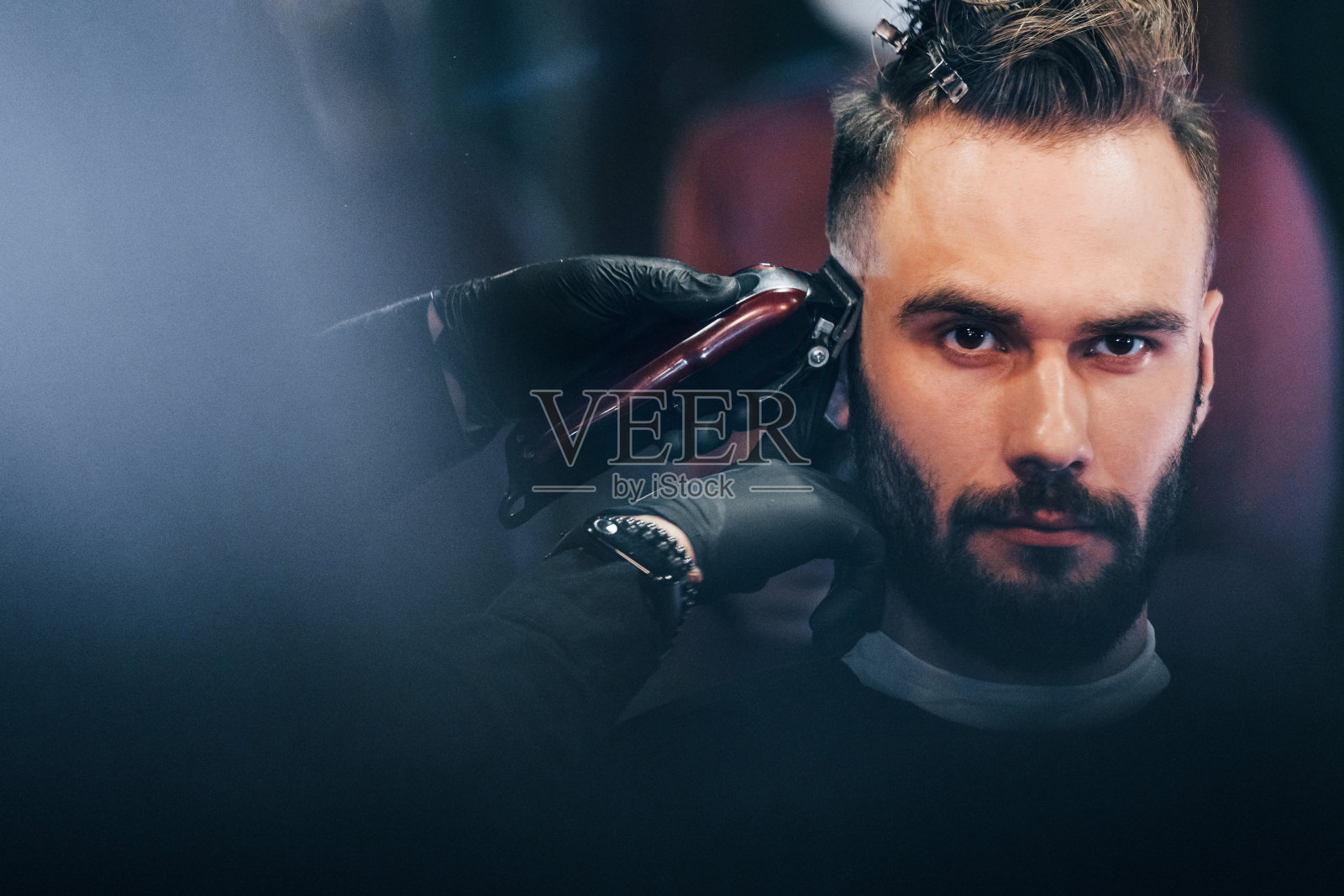 一个留着胡子的年轻人坐在理发店里理发照片摄影图片