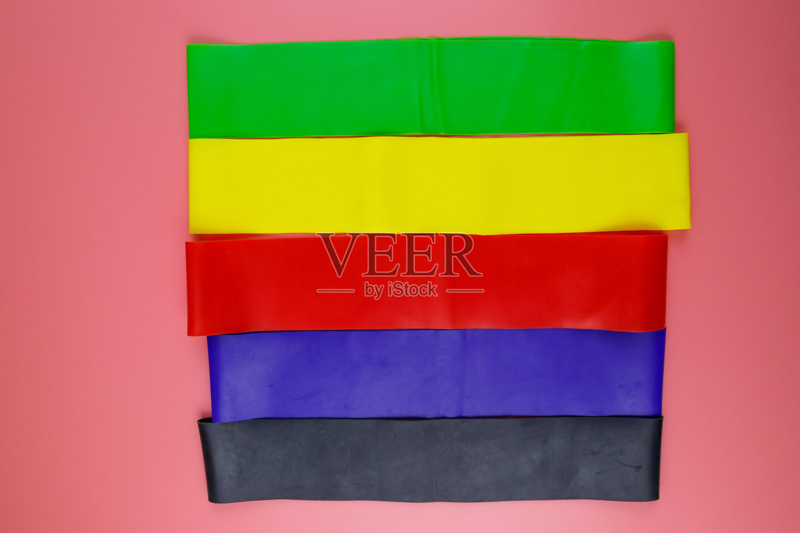 一套弹性橡皮筋为健身在粉红色的背景。俯视图照片摄影图片