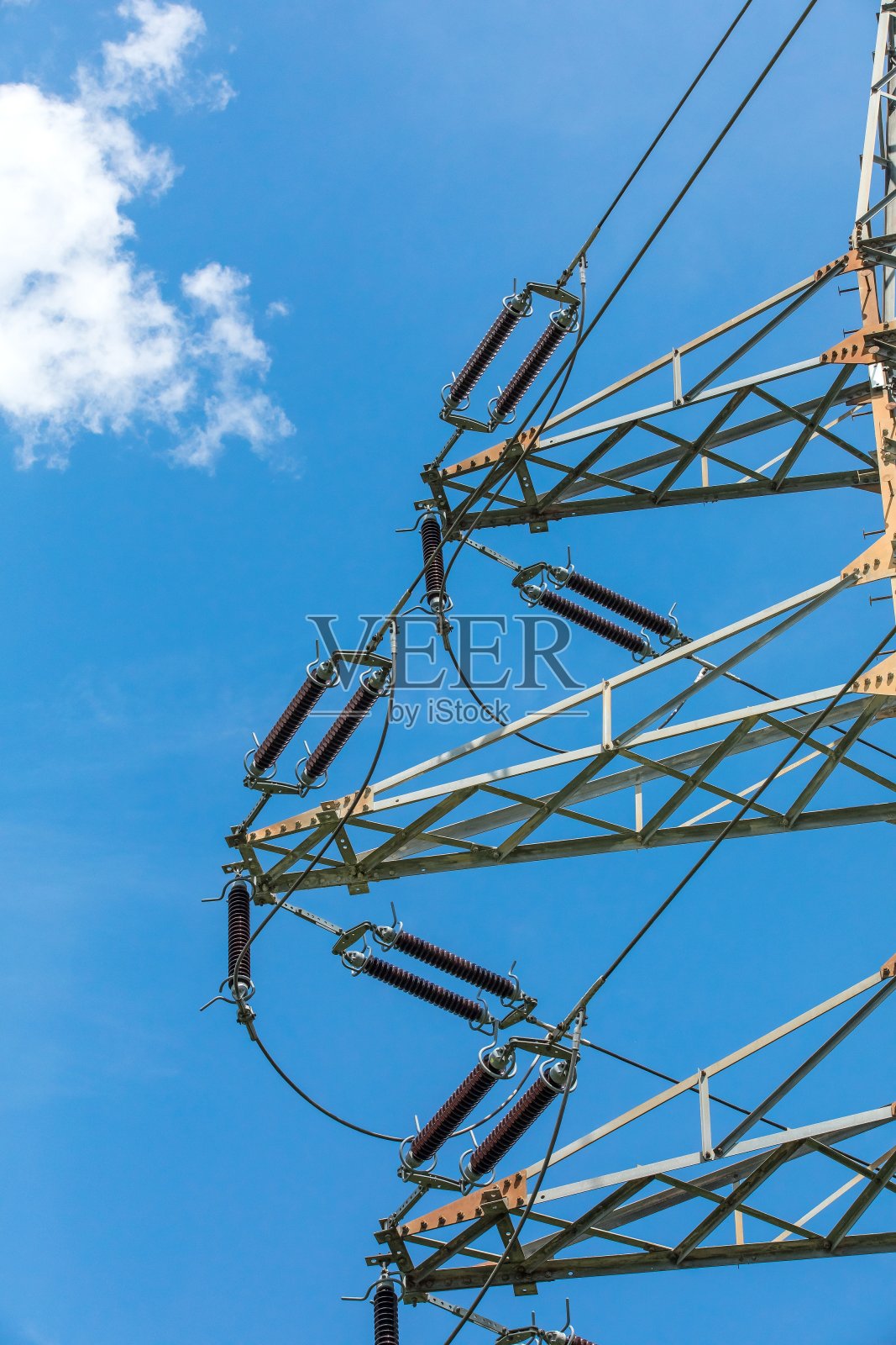 高压输电用电瓷绝缘体。高压电塔对抗多云的蓝天。电力分布。照片摄影图片