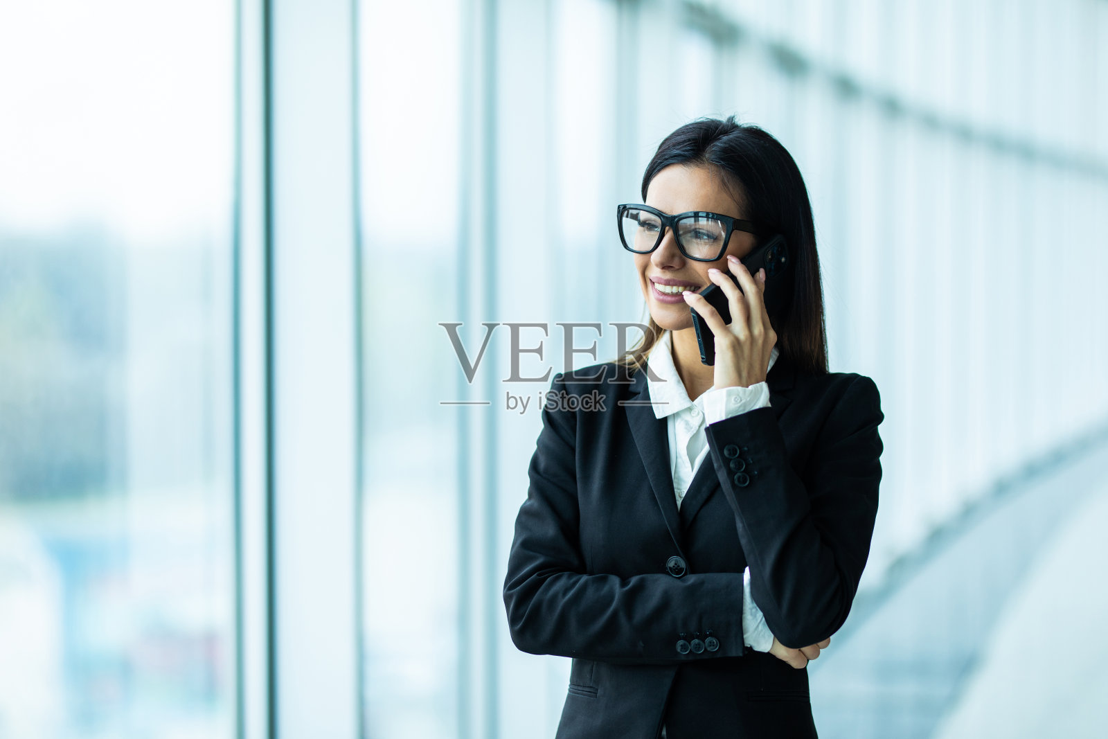 年轻女人在现代的办公室里打电话照片摄影图片