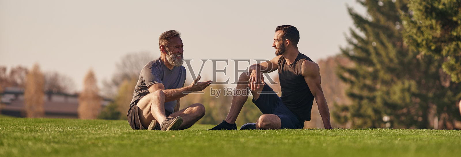 父子俩坐在草地上聊天照片摄影图片