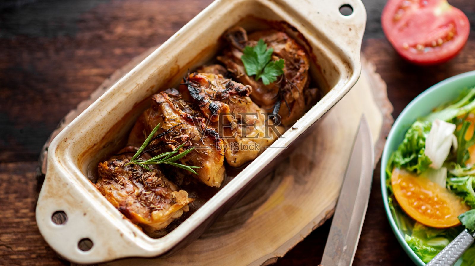 烤鸡腿放在烤盘里,木质背景。照片摄影图片