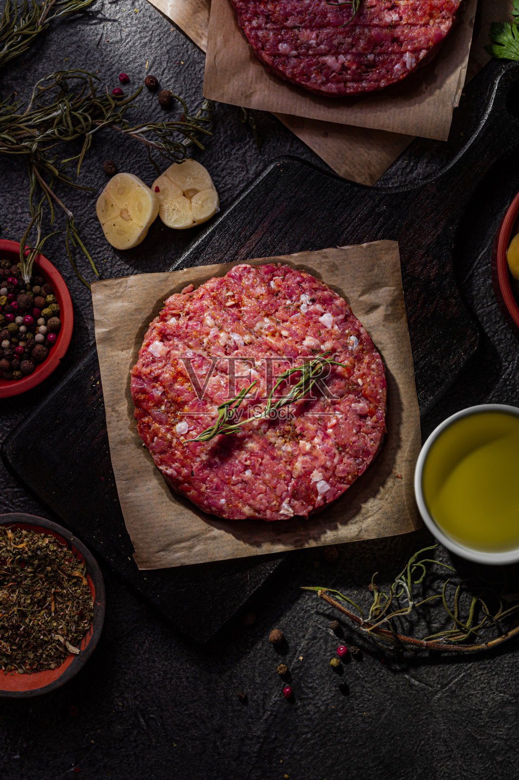 生猪肉汉堡肉排与香料在黑暗的背景。国内生产半成品。照片摄影图片