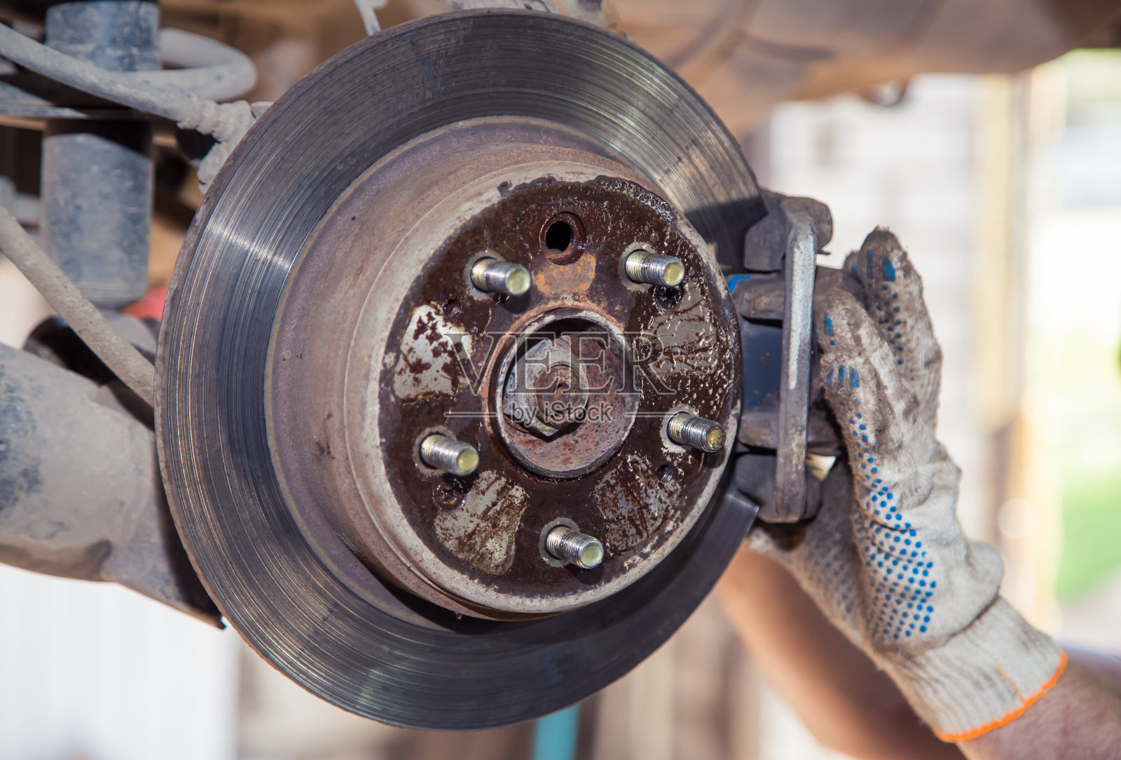 戴着手套安装或拆卸旧汽车的制动钳照片摄影图片