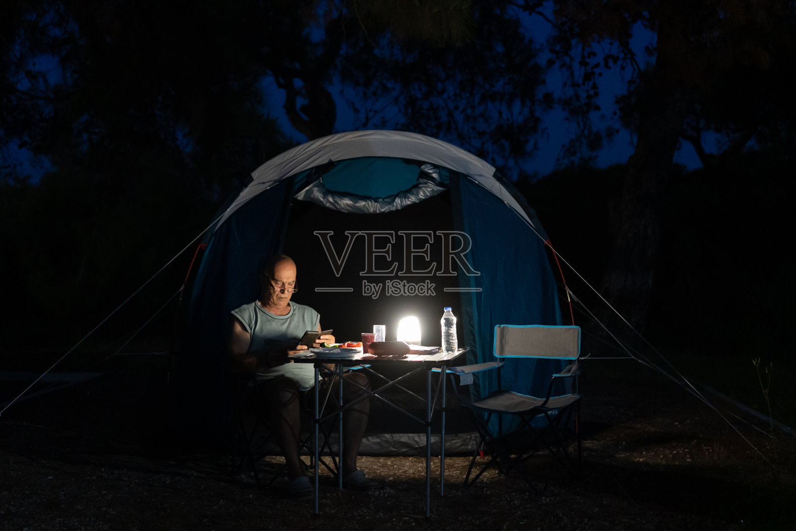 一个老人在露营的时候一边放松一边用手机照片摄影图片