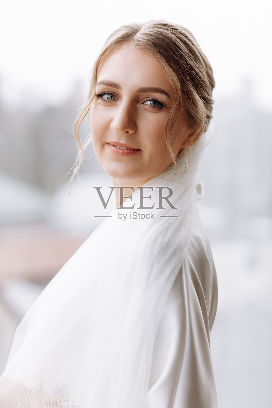 上午的新娘。华丽的新娘。窗外站着一位披着白袍的长发美女。新娘结婚前的早晨。自然美,专业化妆。皮肤护理产品照片摄影图片