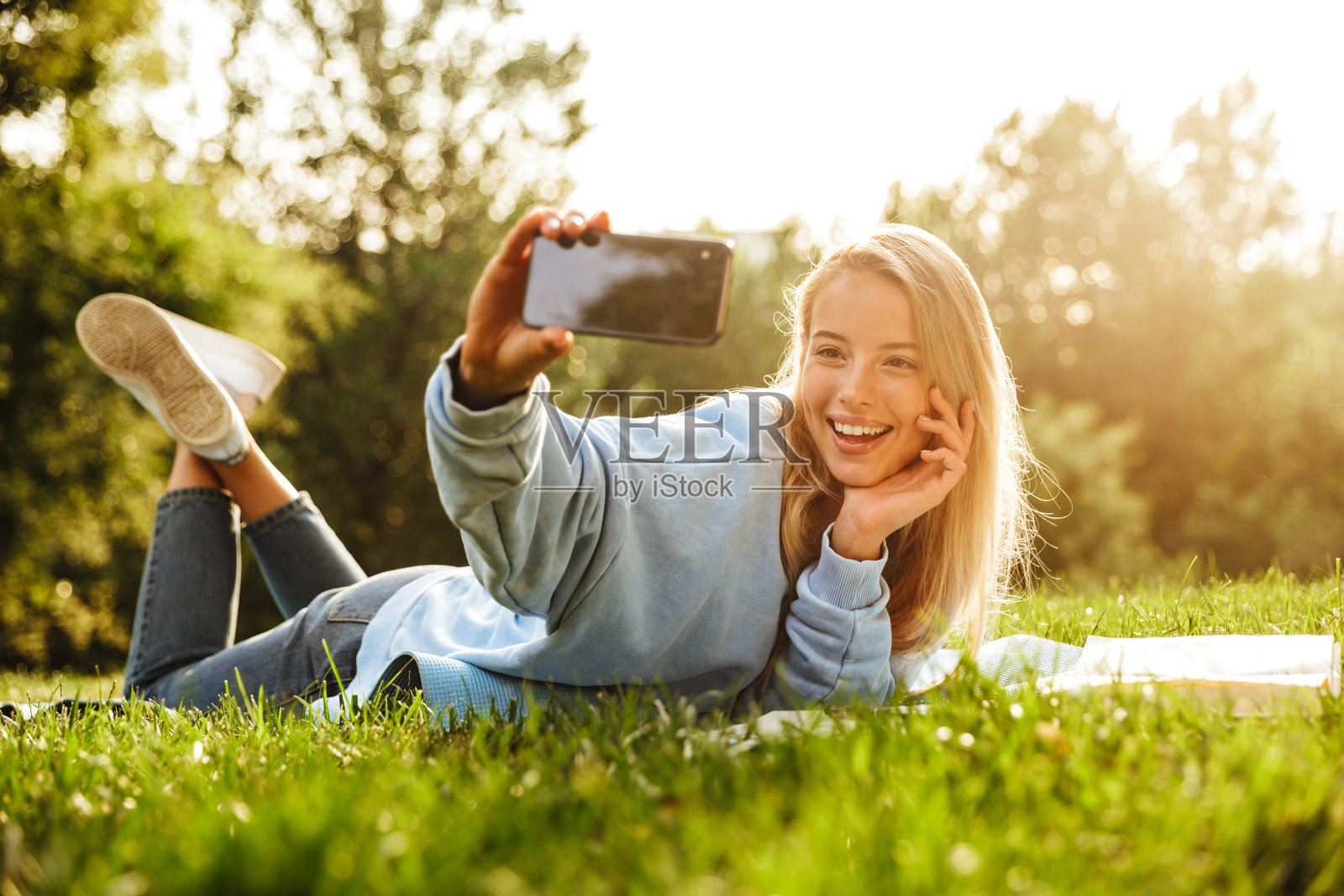 一个可爱的年轻女孩的肖像拿着书躺在草地上照片摄影图片