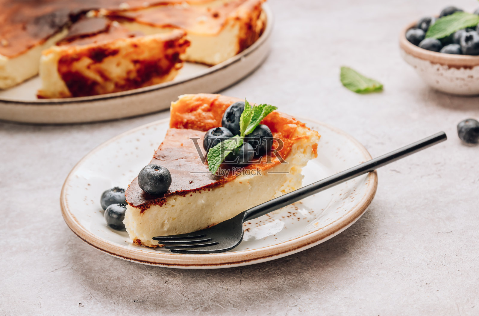 一块巴斯克烤芝士蛋糕放进去,整个蛋糕都在背景中。Tarta de Queso。照片摄影图片