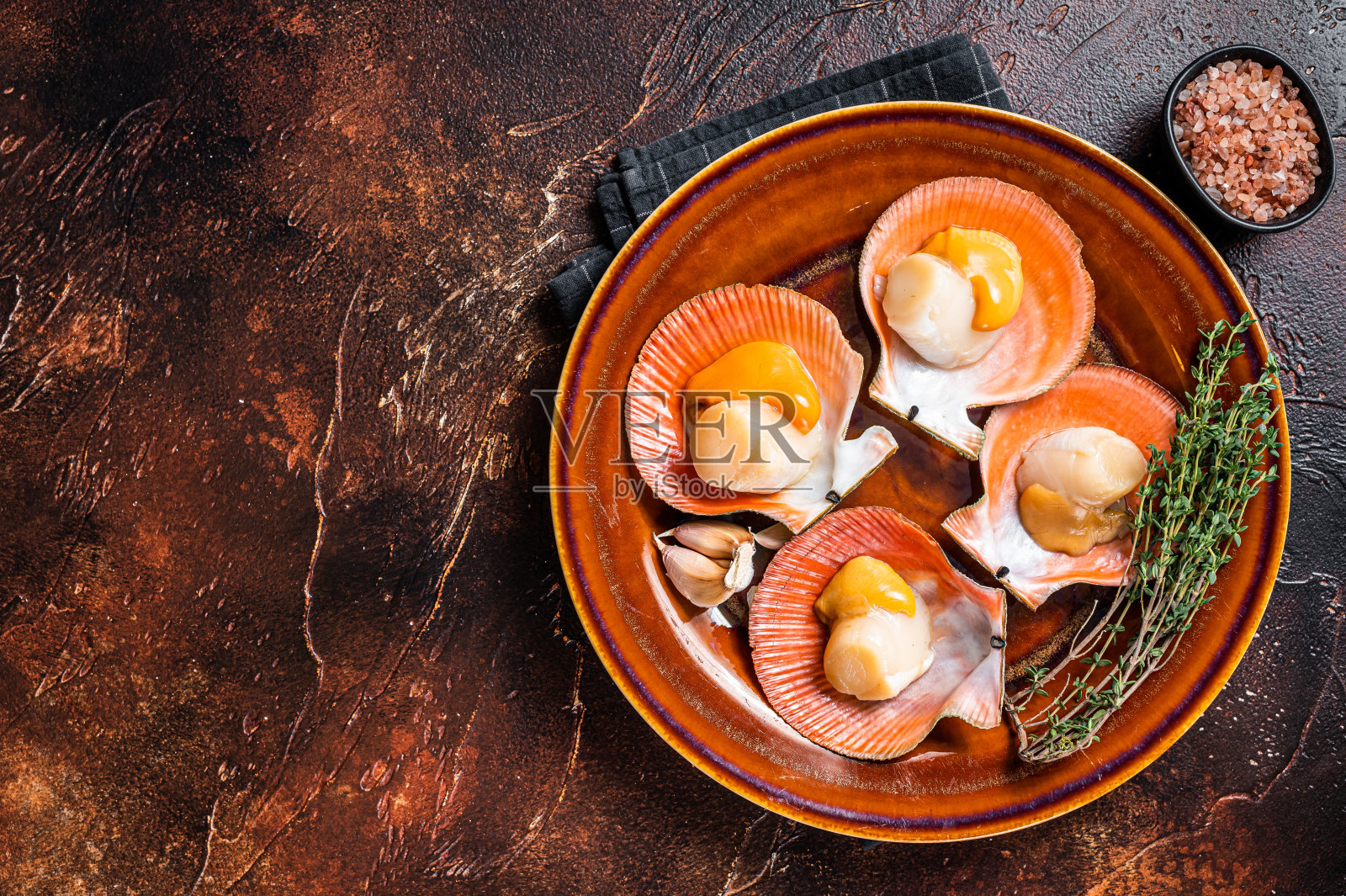 带百里香的乡村盘子里放着生扇贝。黑暗的背景。前视图。本空间照片摄影图片