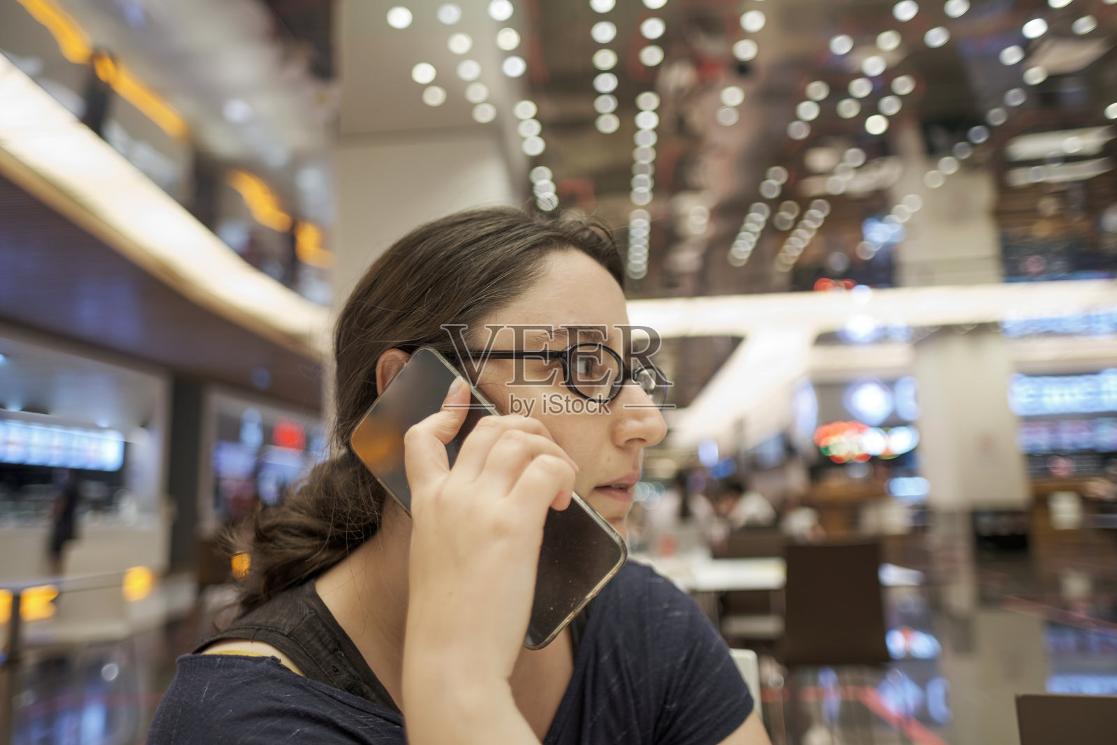 选择焦点的一个年轻的黑发女人与眼镜交谈的智能手机照片摄影图片