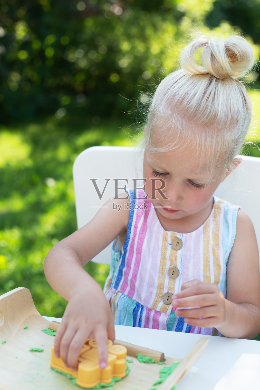 一个可爱的金发小女孩在夏天的后院玩动态的沙子照片摄影图片