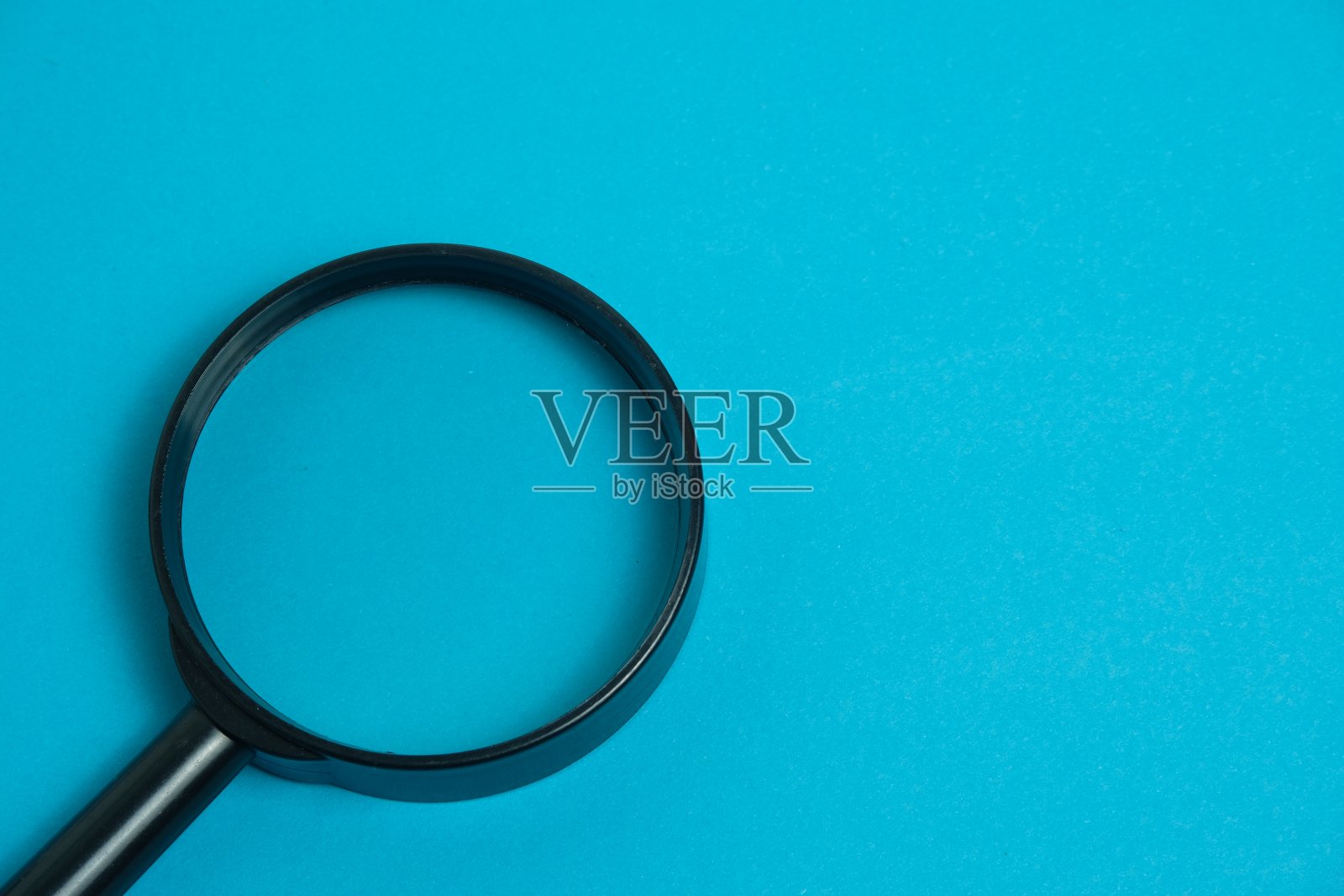 近距离放大镜或放大镜隔离在蓝色背景。照片摄影图片