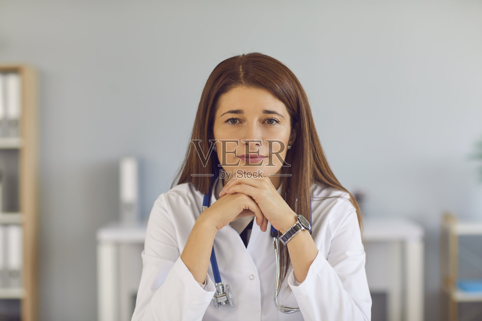 一个年轻疲惫的红发女医生的肖像坐在桌子上,靠在她的手。照片摄影图片