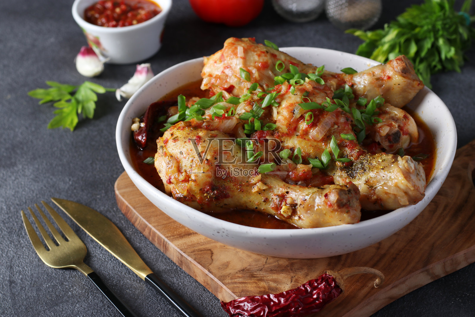 格鲁吉亚的肉菜,鸡肉和西红柿放在深灰色的木板上。特写镜头照片摄影图片