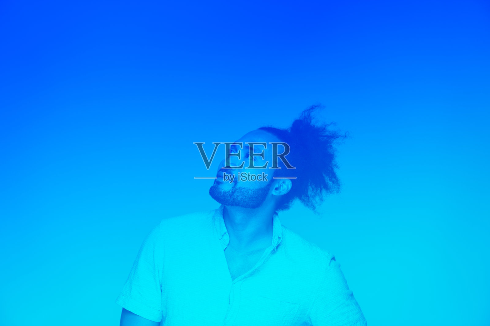 在蓝色背景下向上看的鬈发打结的黑人照片摄影图片