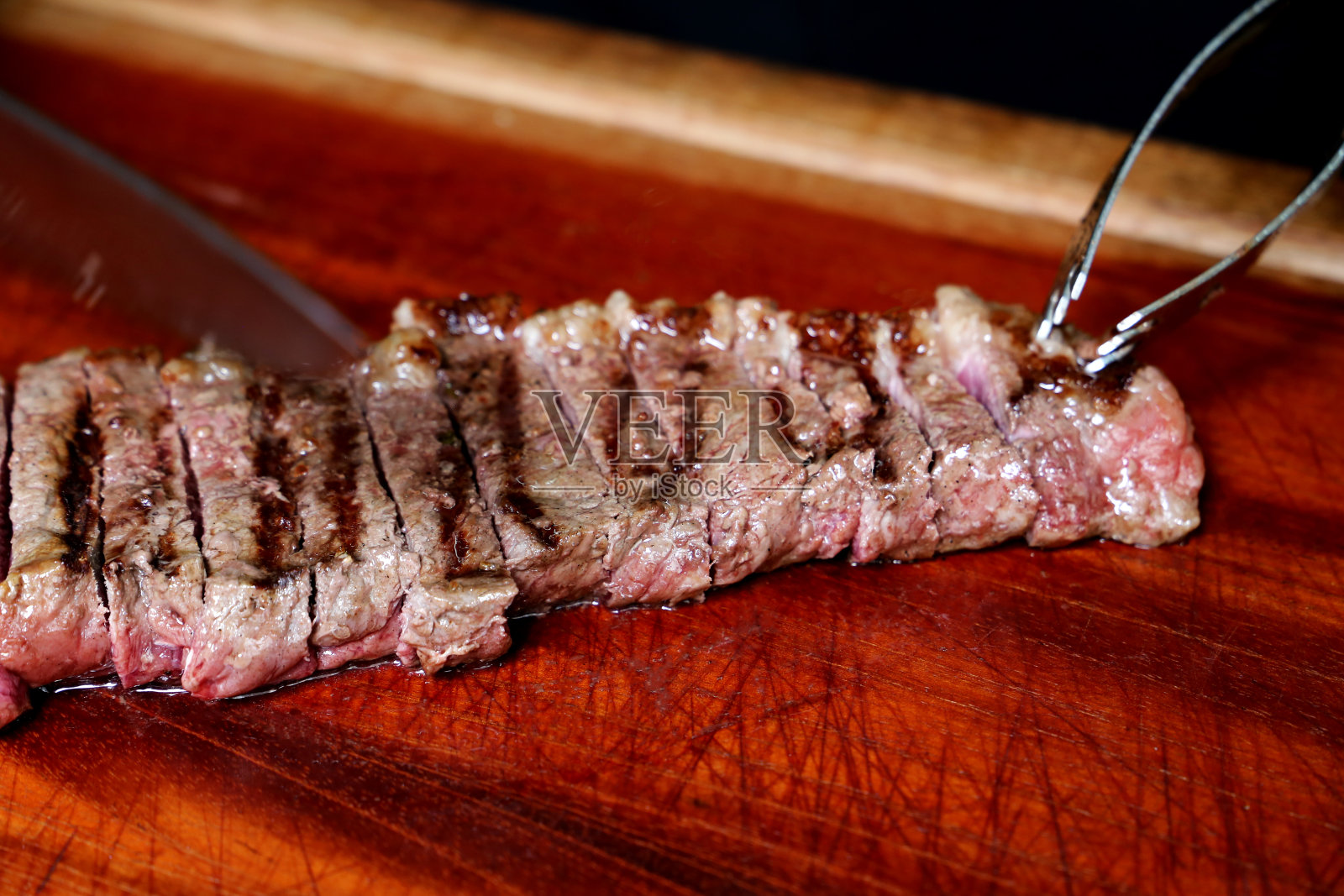 Picanha或臀肉牛排。手戴黑手套在木板上切多汁的牛排照片摄影图片