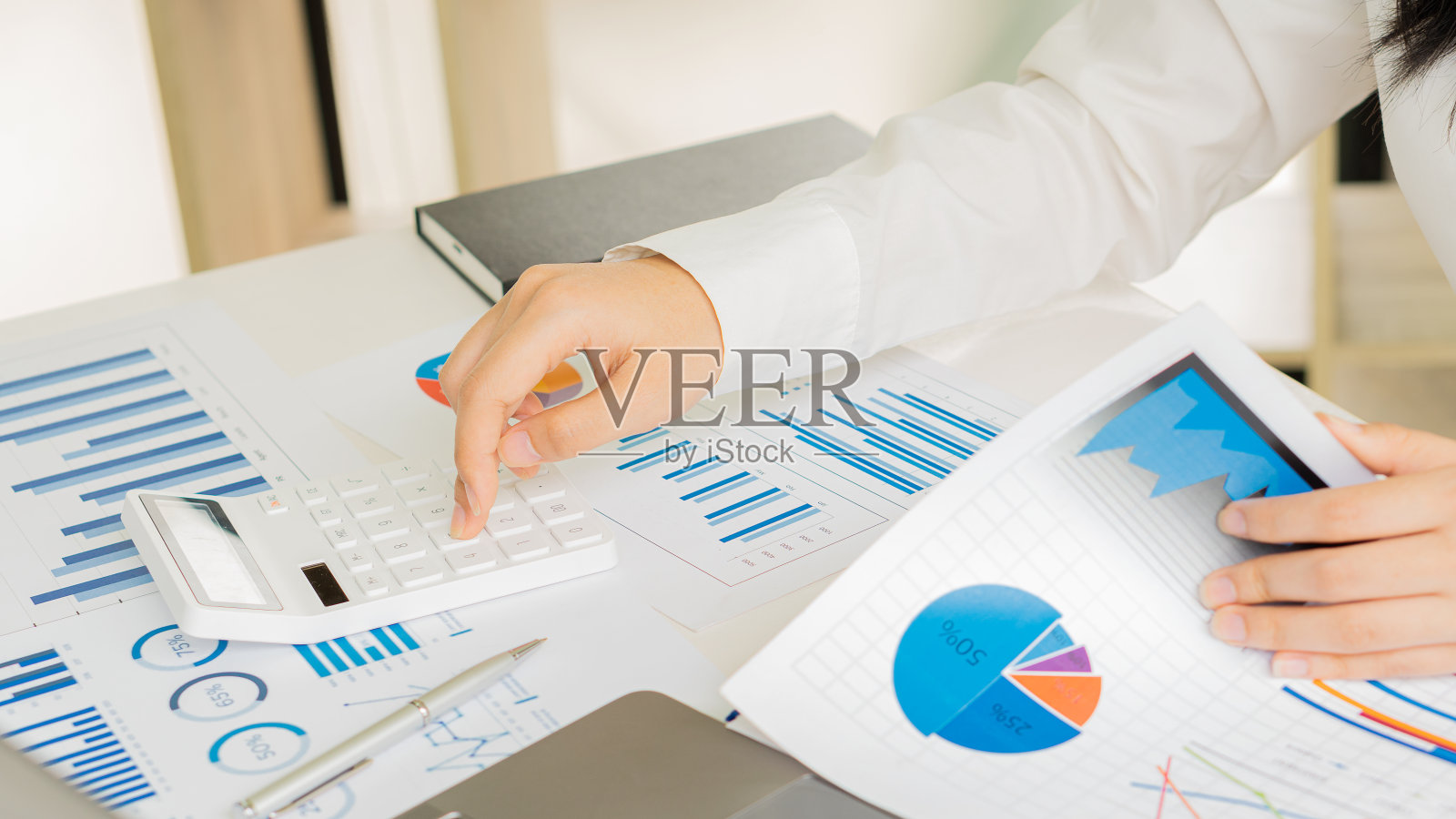 一个商人在办公室工作,带着一台笔记本电脑和一个办公桌图表数据表和一个计算器来计算和分析。照片摄影图片